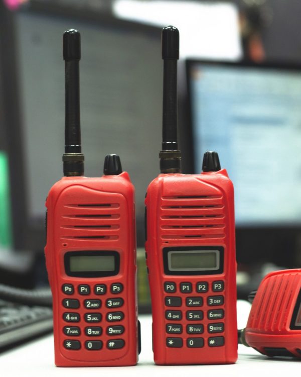Red Walkie-talkie radio on wooden table operator in office.